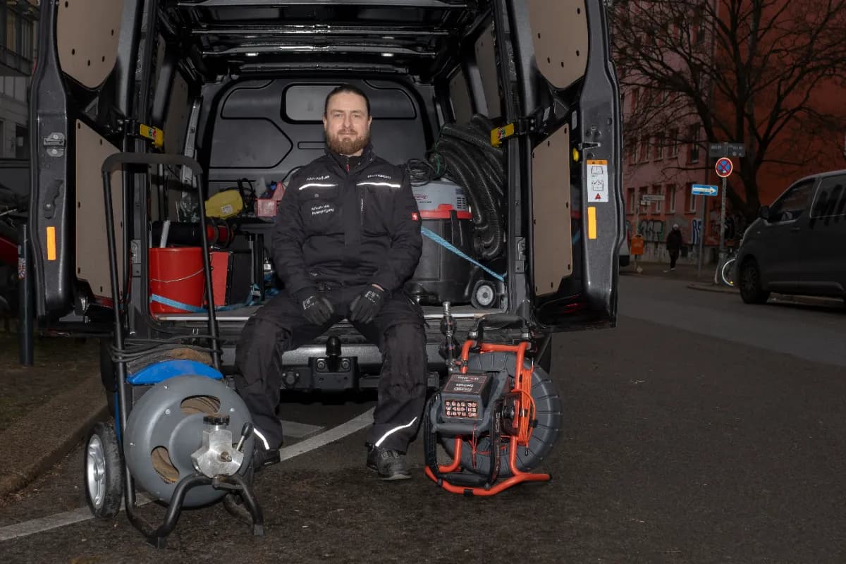 Techniker reinigt Dachrinne am Haus des Kunden